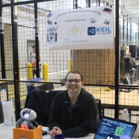 A student siting at a table with a poster and a laptop.
